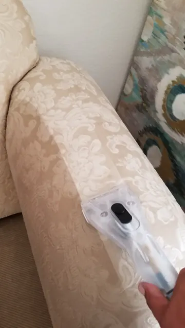 Hand tool extracting dirt from a sofa arm